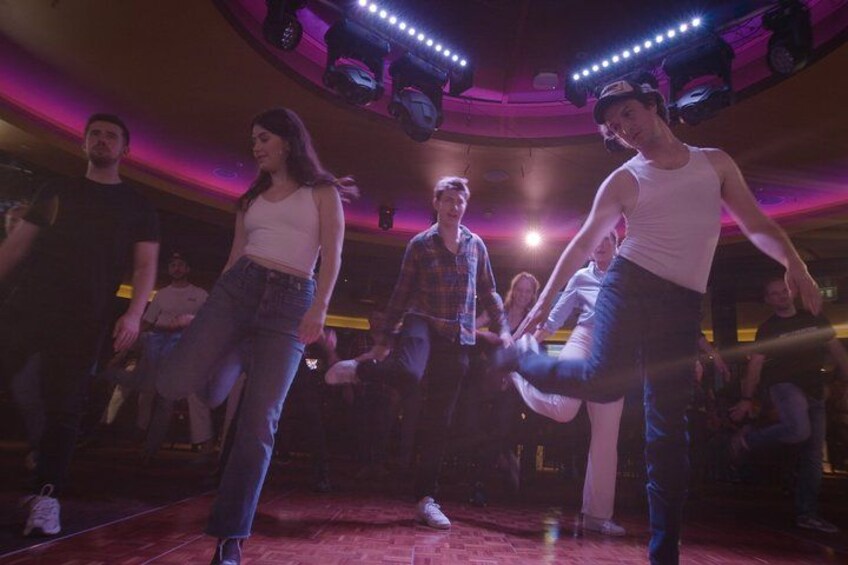 A dance performance with a circular stage and audience in a dimly lit venue. 5