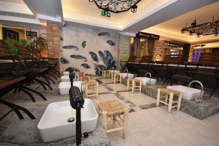 A spa area with multiple tubs, benches, and a mural of fish on the wall. 4