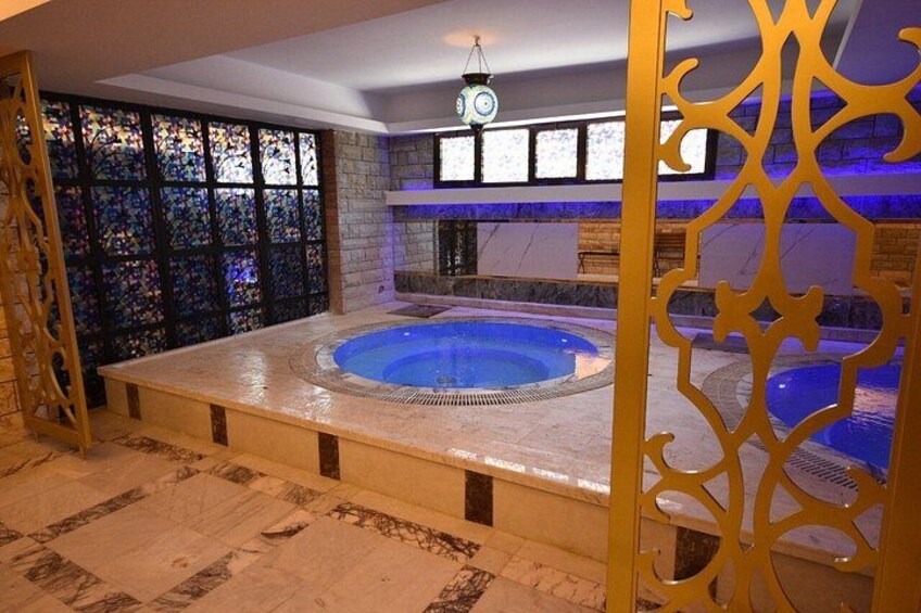 A hot tub in a room with a decorative wall and a clock. 2