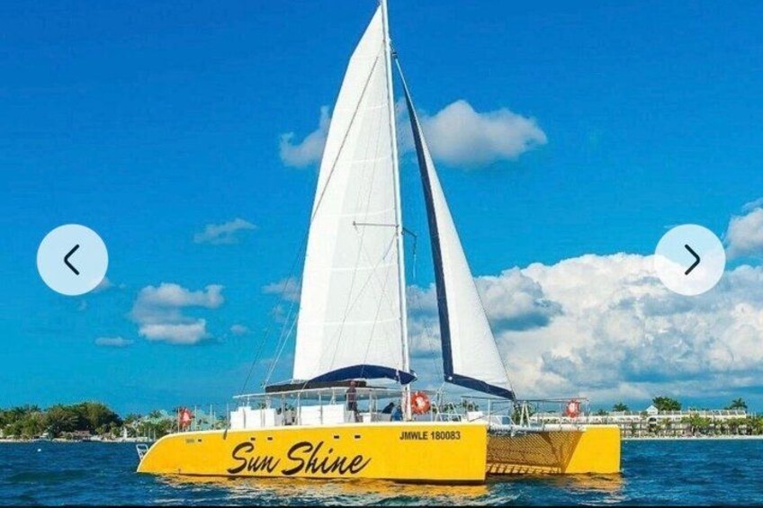 A yellow sailboat named 'Sun Shine' with the registration number JMWE 160083 sailing on the water. 2