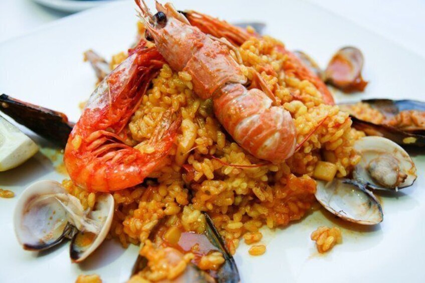 A plate of seafood paella with shrimp, clams, and rice. 3