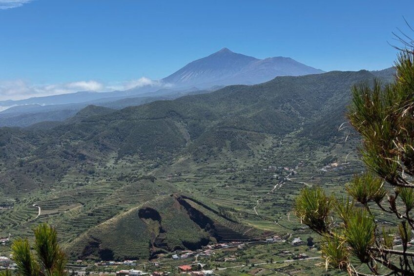 A mountainous landscape with a prominent volcano in the background, terraced fields, and a clear sky. 5