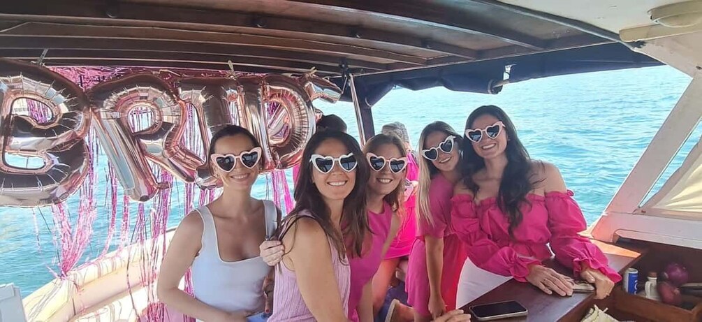 A group of people on a boat with heart-shaped balloons and a clear blue sky. 4