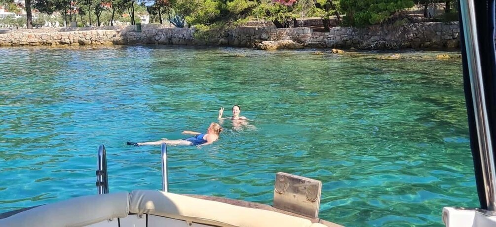 A person swimming in clear water with a boat in the foreground. 5