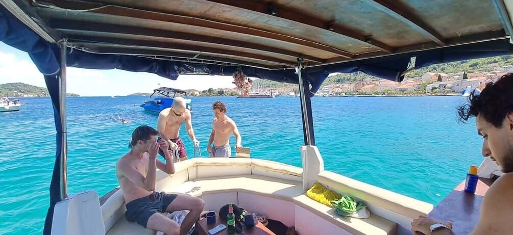 A boat with people on board, a clear blue sea, and a distant shoreline with buildings. 3