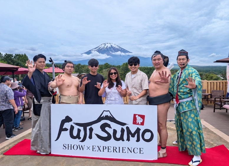 A group of people posing in front of a sign with a mountain in the background. 5