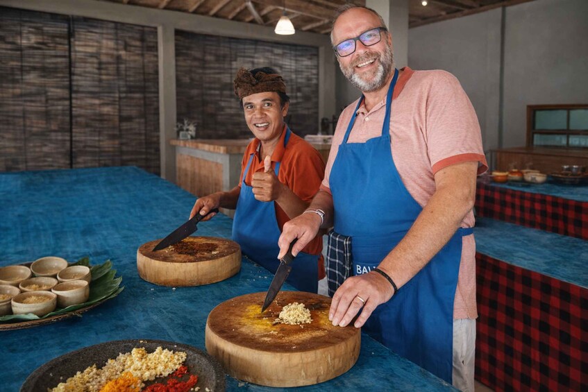 Two people preparing food, one chopping on a wooden board and the other mixing ingredients on a cutting board. 2