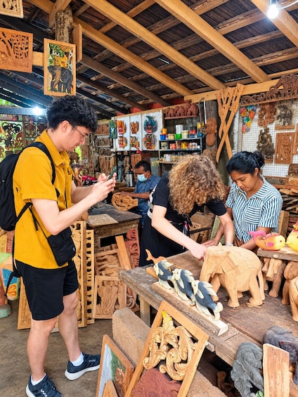 A workshop with wooden carvings, including elephants and birds, and a person working on a wooden piece. 3