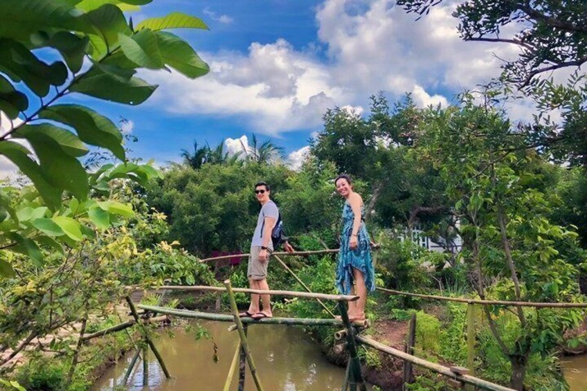 Two people standing on a wooden bridge over a water body, surrounded by greenery. 2