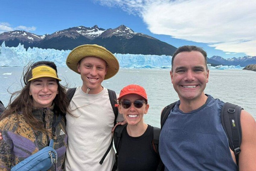 A group of people standing in front of a glacier with mountains in the background. 3