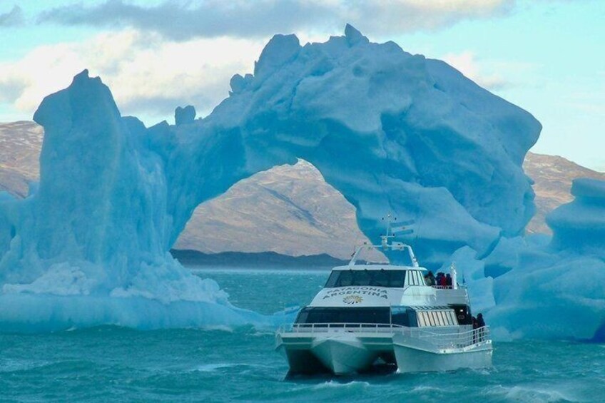 A boat navigating through a large ice arch in a body of water. 2