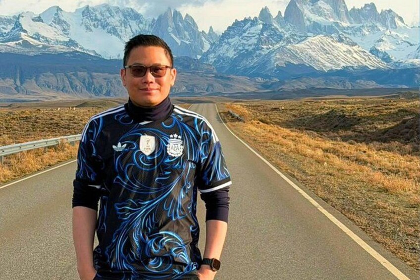 A person standing on a road with a mountainous landscape in the background. 2