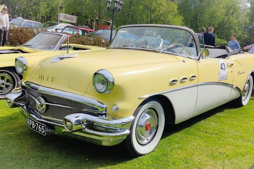 A vintage yellow convertible car with a number plate RPB-7655, parked on grass at a car show. 1