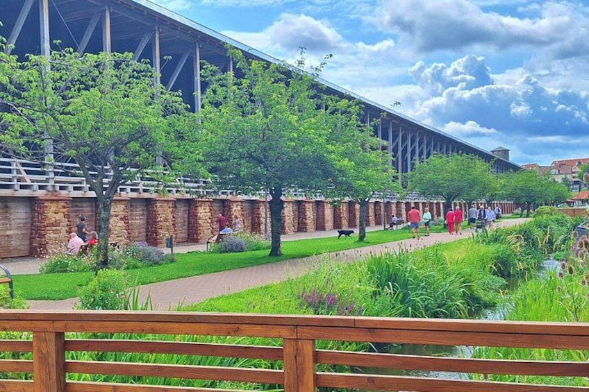 A pathway lined with trees and a brick wall, with people walking and sitting. 4