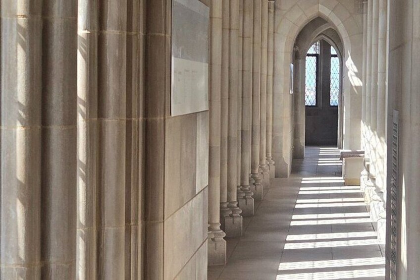 A long corridor with tall columns, a tiled floor, and a door at the end. 3