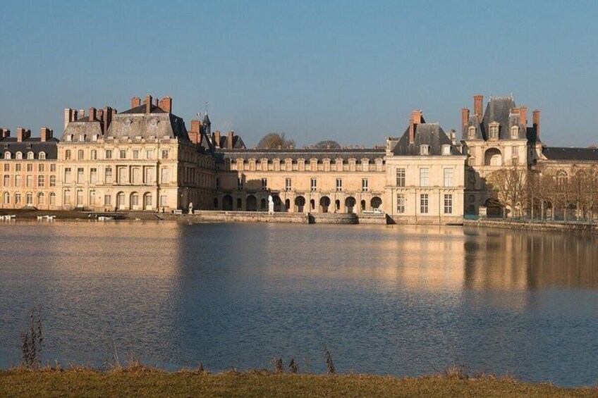 A historic building with multiple towers and a reflective water body in the foreground. 2