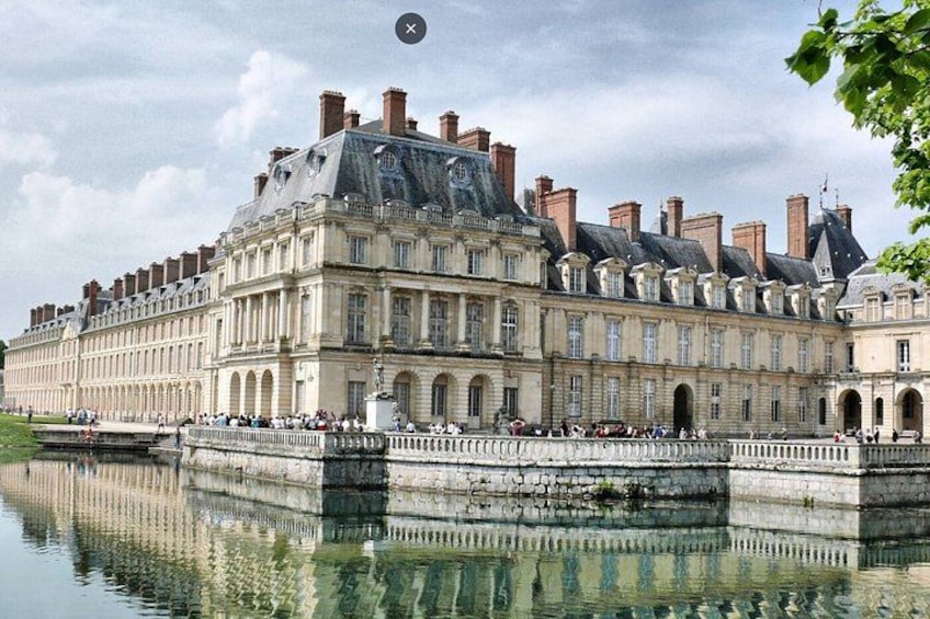 A large historic building with a reflective water body in front. 1