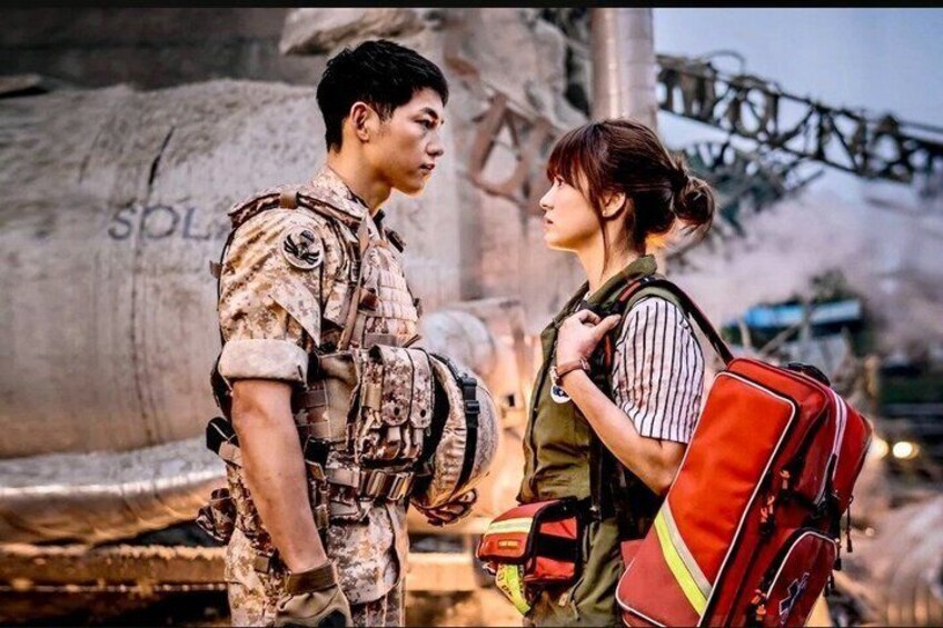 A person in military attire standing next to another person with a red backpack. 1