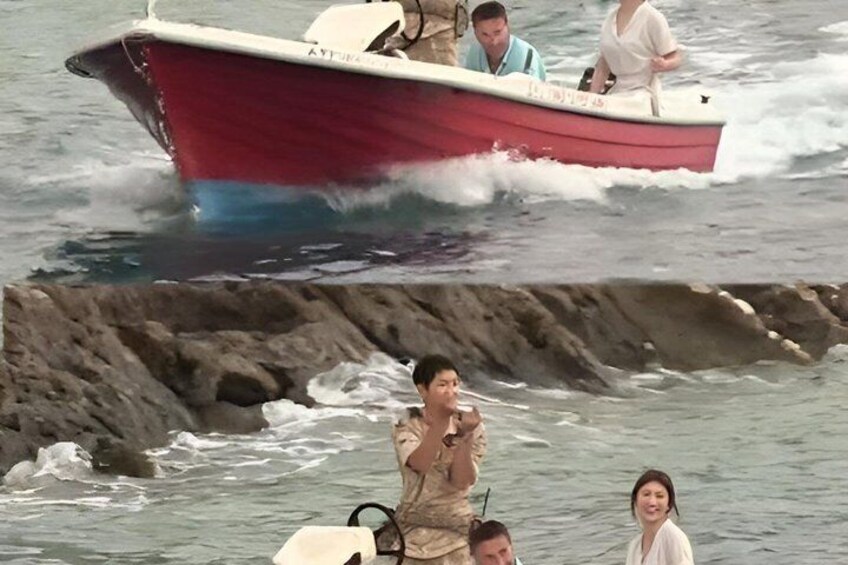 A red boat with people on it, a rocky shoreline, and a person taking a photo. 3