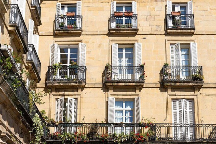 A multi-story building with balconies, shutters, and flower boxes. 2