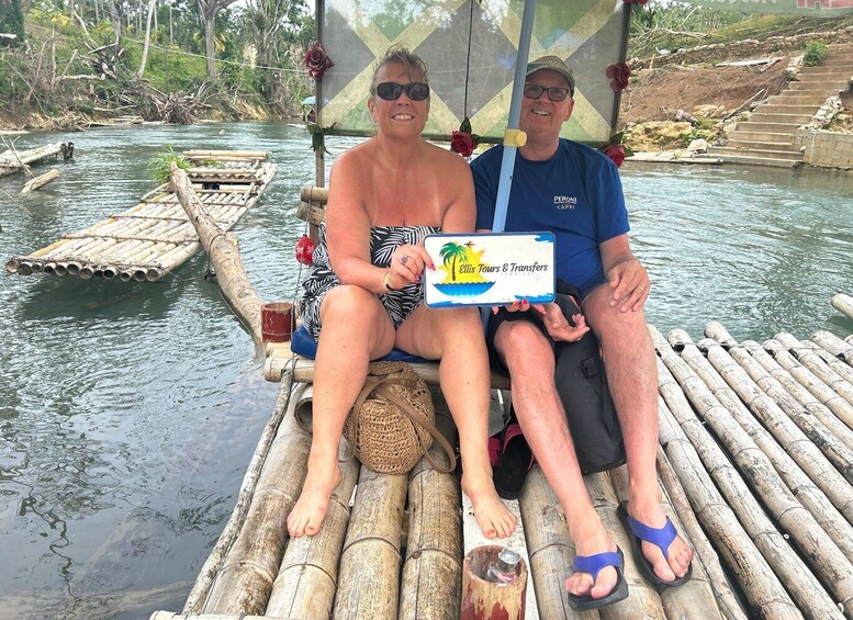 Two people on a bamboo raft in a river with a sign for Ellis Tours & Transfers. 3