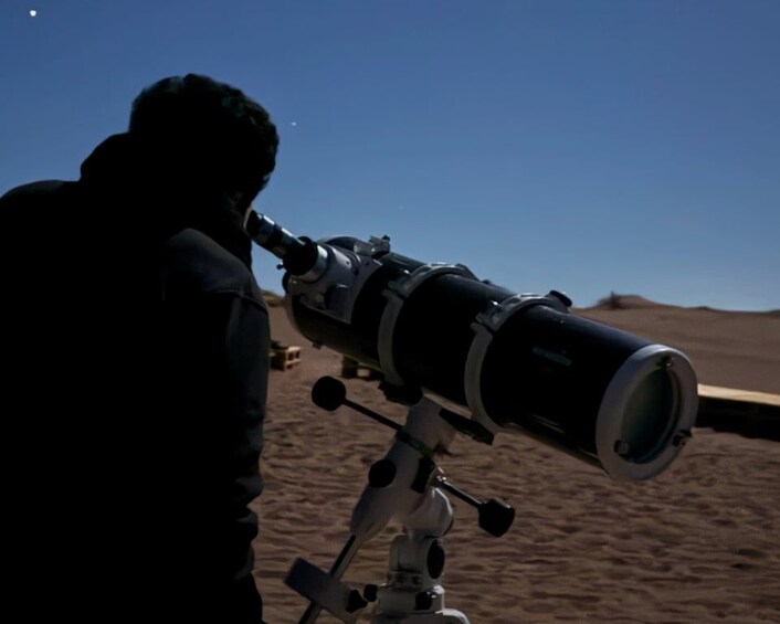 A person using a telescope on a sandy terrain. 5