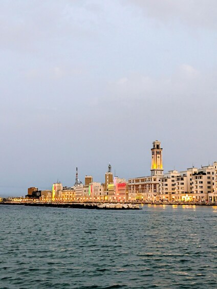 A coastal cityscape with a prominent tower and a row of colorful buildings along the waterfront. 3