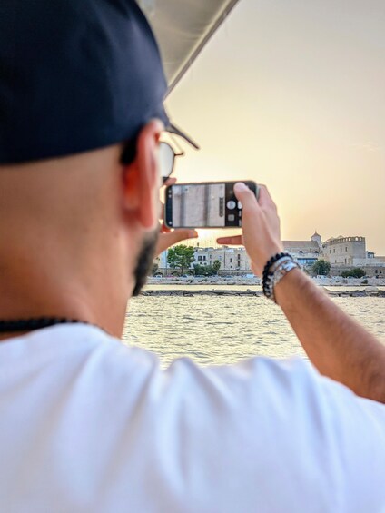A person taking a photo with a smartphone of a waterfront cityscape during sunset. 5