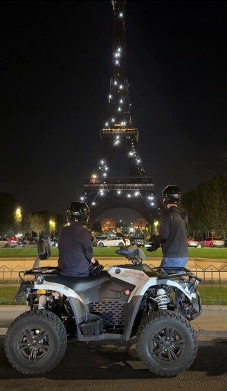 Two people on ATVs facing the Eiffel Tower at night. 5