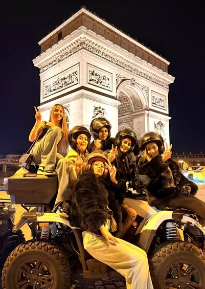 A group of people on an ATV near the Arc de Triomphe at night. 2