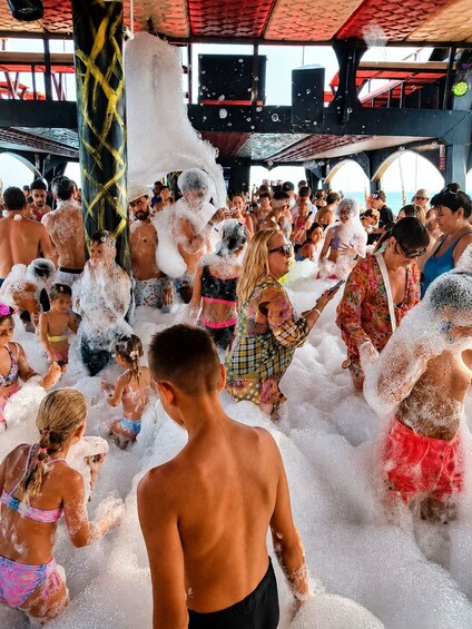 A crowded indoor event with people covered in foam. 4