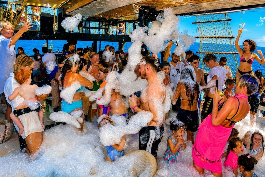 A group of people enjoying a foam party on a boat. 3