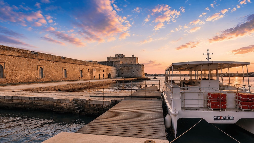 A boat docked at a pier with a historic building in the background. 2