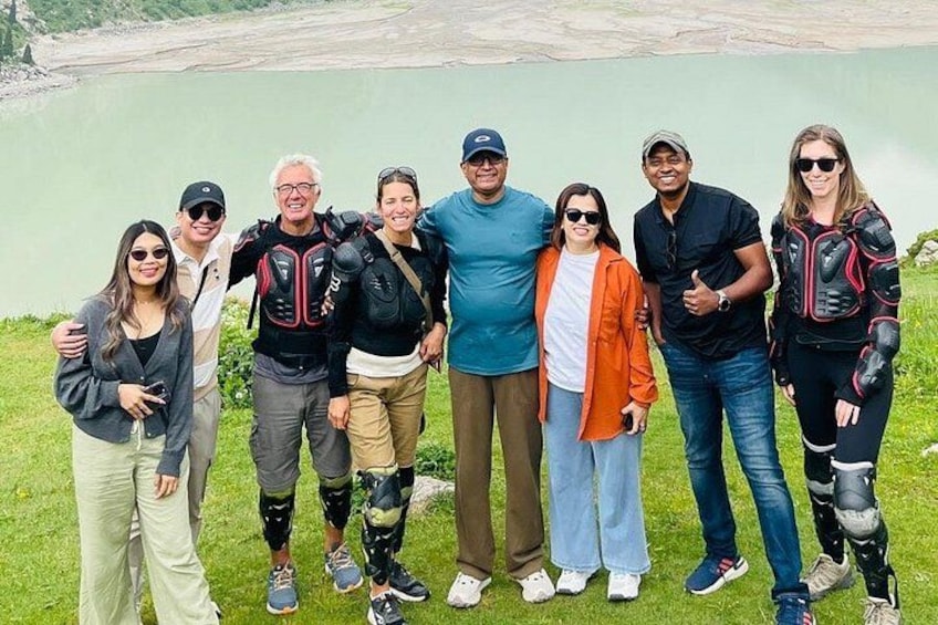 A group of people standing in a grassy area with a body of water in the background. 4