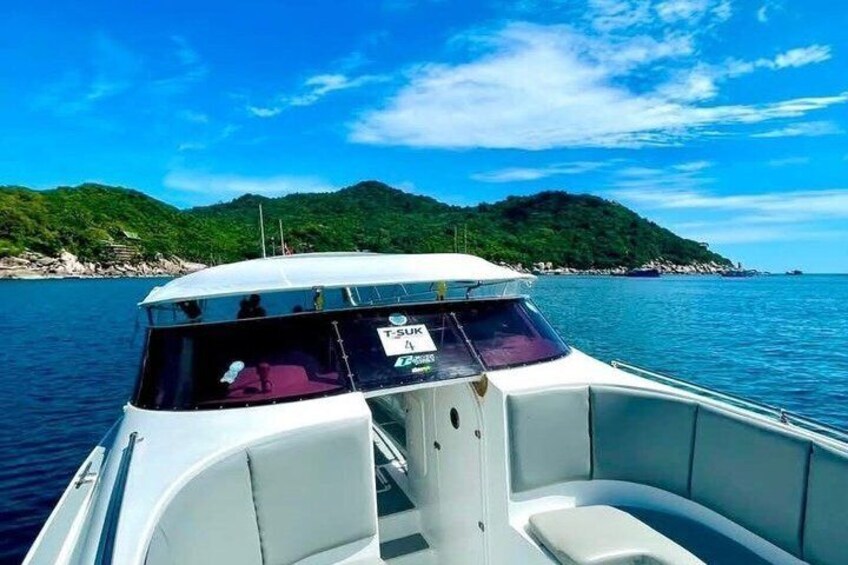A boat on calm water with a clear sky and a hilly landscape in the background. 2