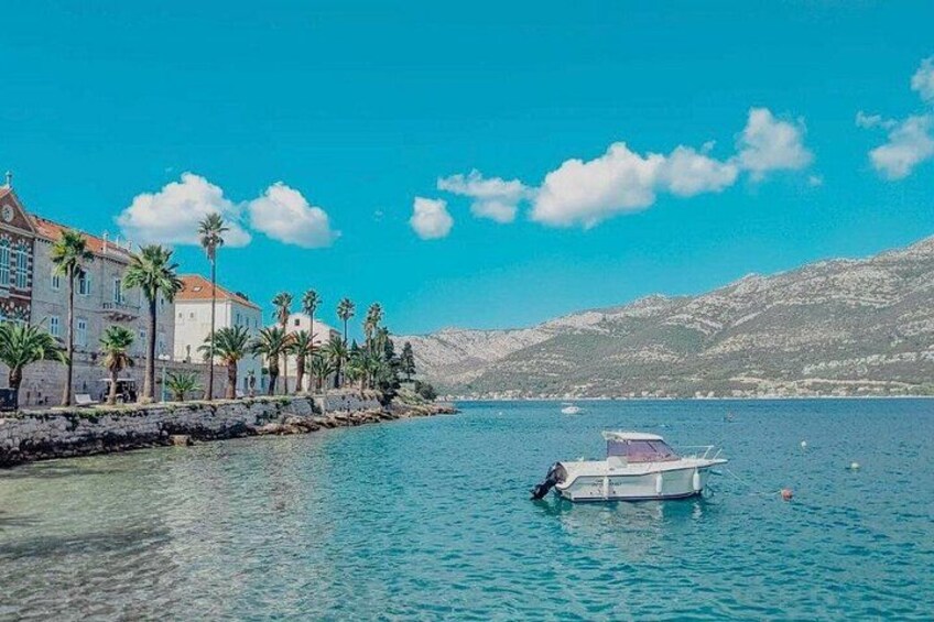 A coastal town with buildings, palm trees, and a boat on the water. 3