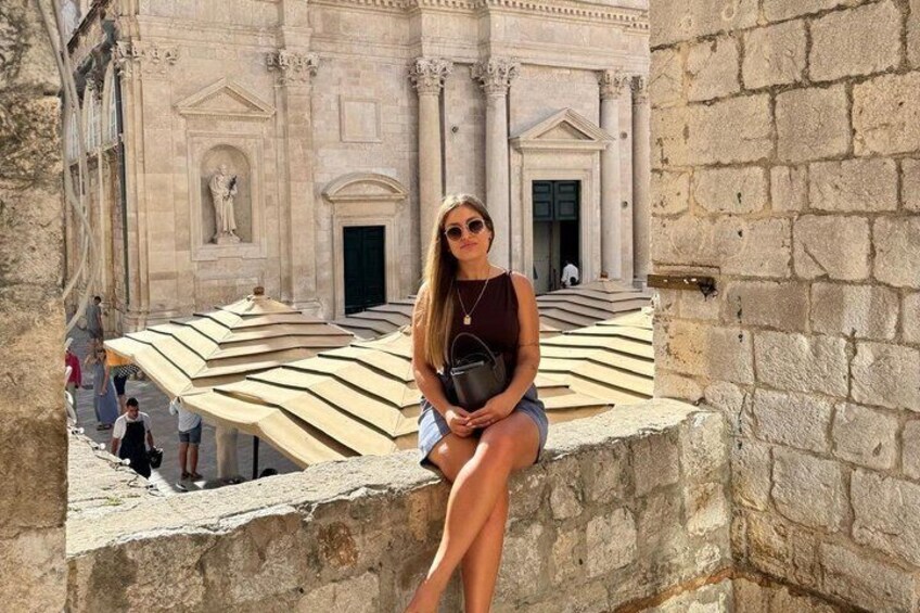 A person sitting on a stone ledge with a building in the background. 3