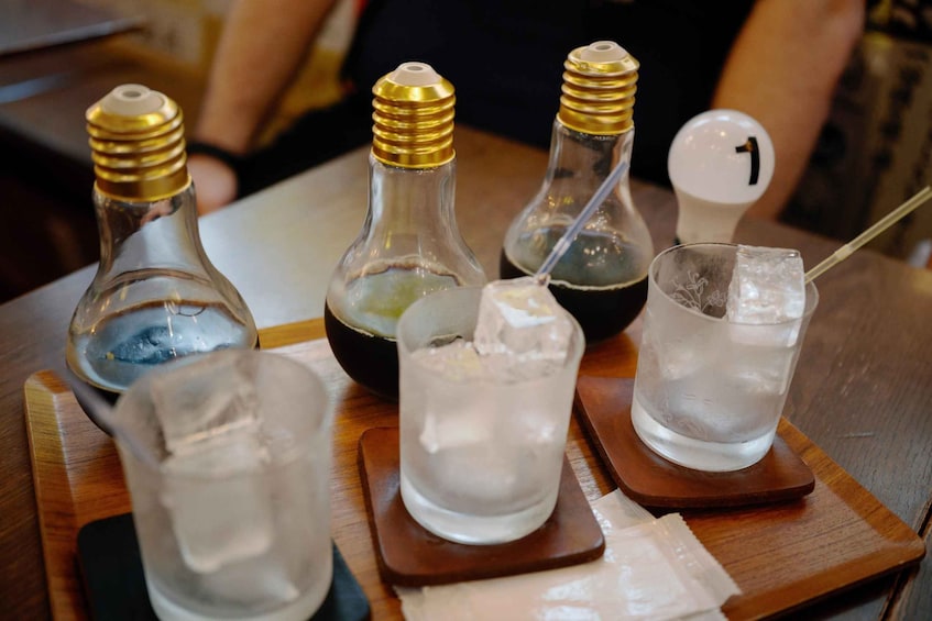 A table with four bottles and three glasses, each with a wooden coaster. 3