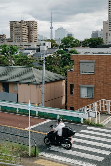 A person riding a motorcycle on a road with buildings and a tower in the background. 4
