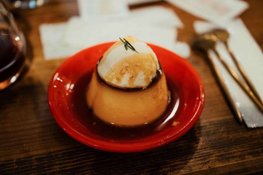 A dessert on a red plate with a caramelized top, possibly a flan or crème brûlée, on a wooden table. 2