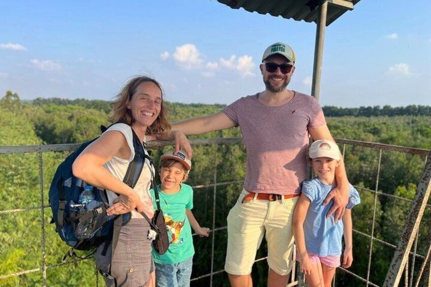 A group of people standing on a bridge with a forested landscape in the background. 4
