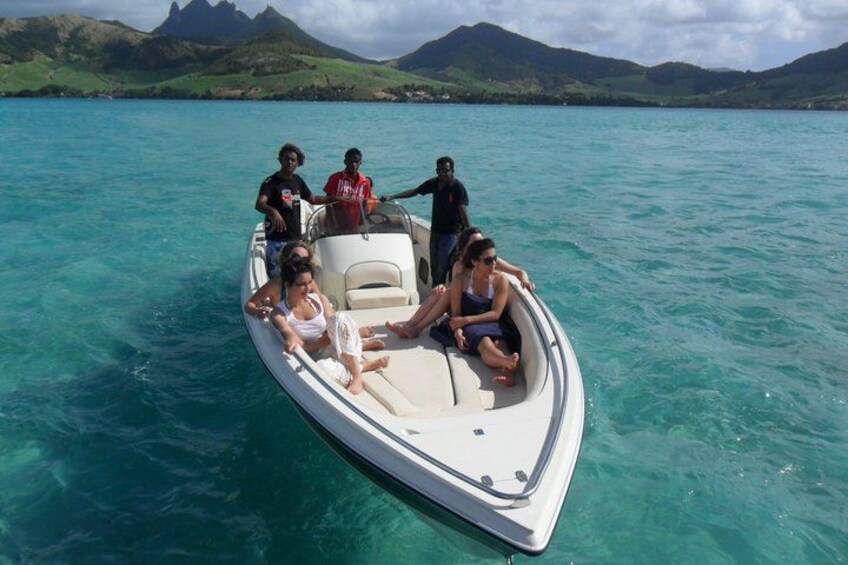 A small boat with people on a turquoise sea, surrounded by green hills. 2