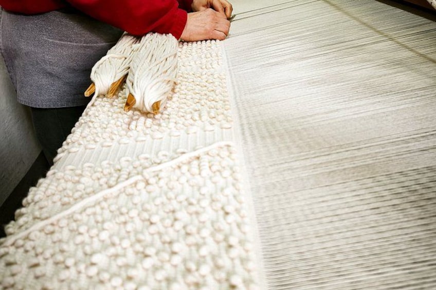 A person weaving on a loom with white threads. 5