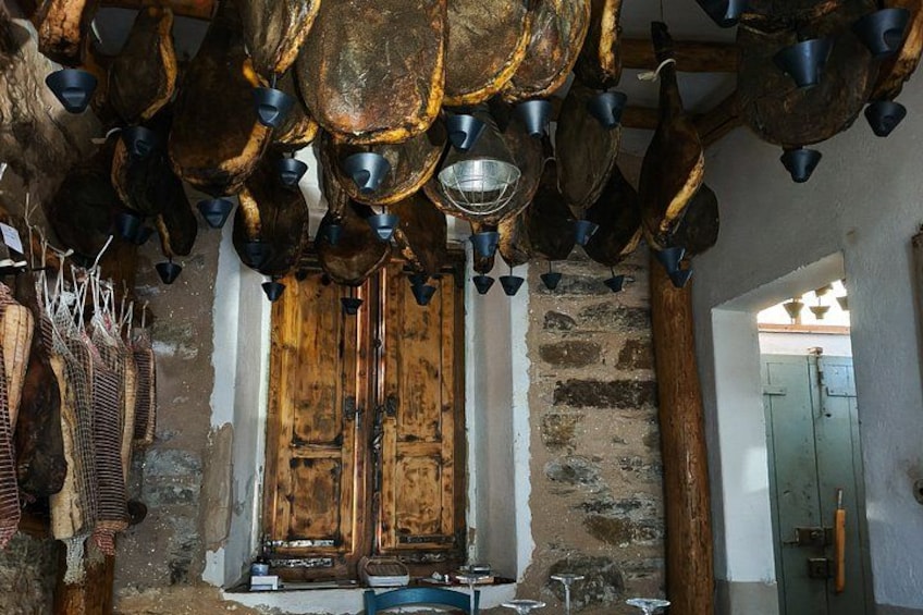 A rustic kitchen with hanging pots and pans, a wooden door, and stone walls. 3