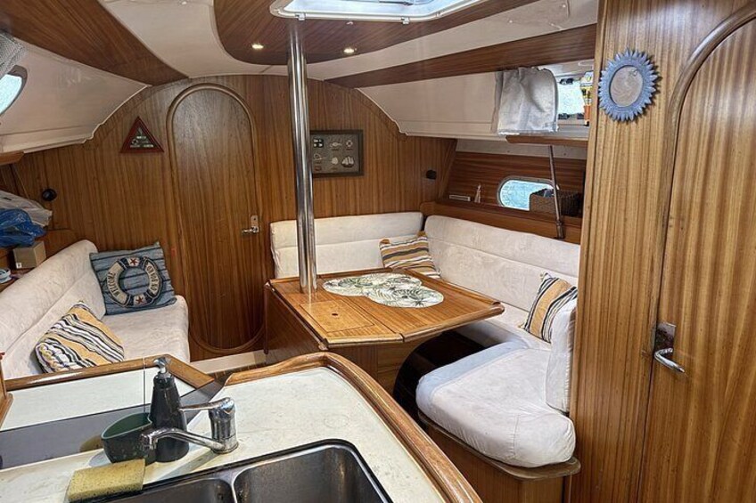 A compact interior with a wooden vanity, a sink, and a cushioned seating area. 3