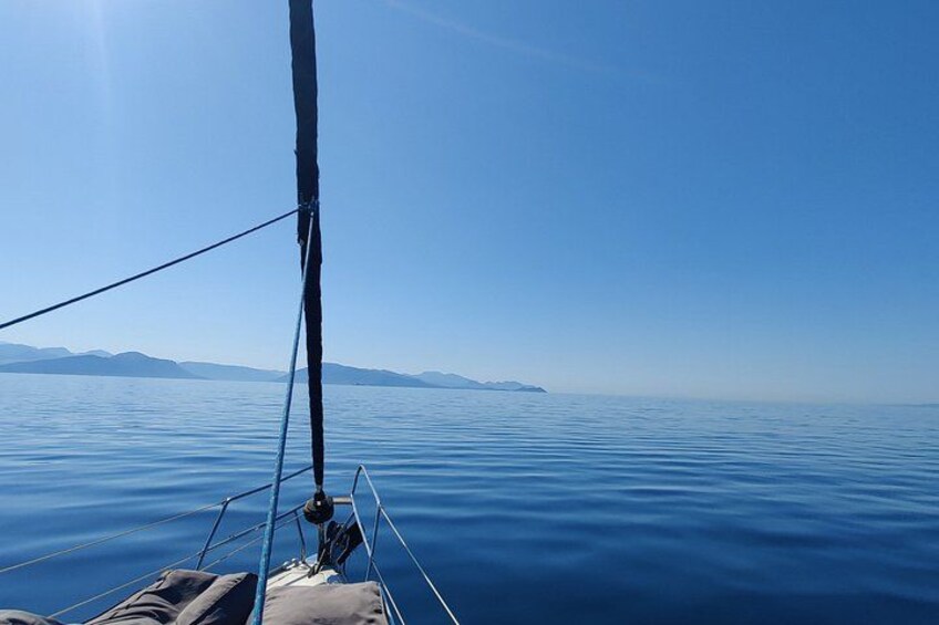 A sailboat's mast and rigging, calm water, and distant land. 2