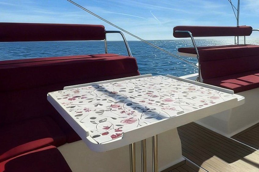A boat deck with a table and red cushioned seating. 4