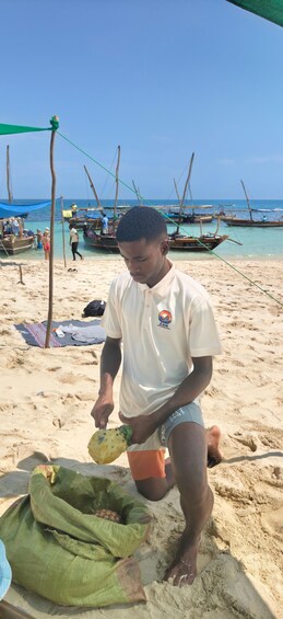 A person on a sandy beach with boats in the background. 2