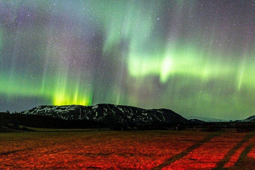 A night sky with the Northern Lights over a snowy landscape with a red-lit road. 4