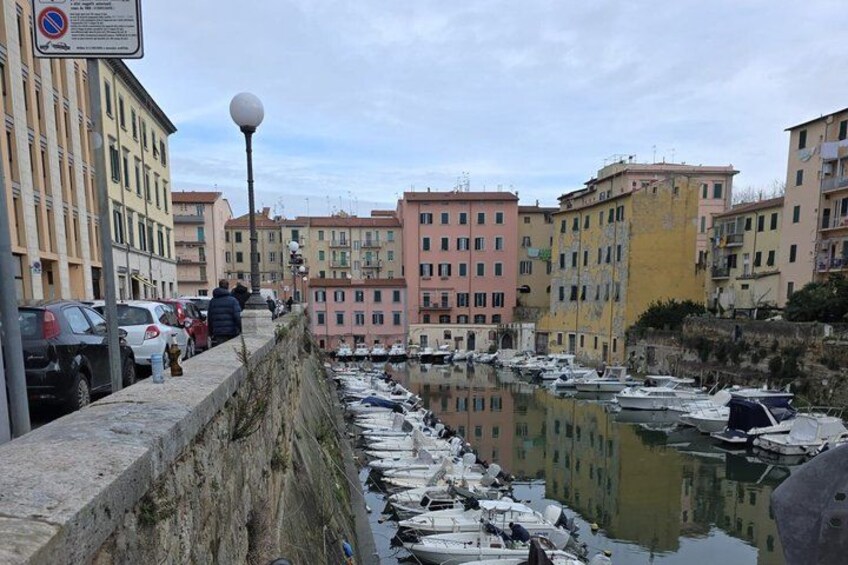 A waterfront with boats docked, buildings, and a no parking sign. 5